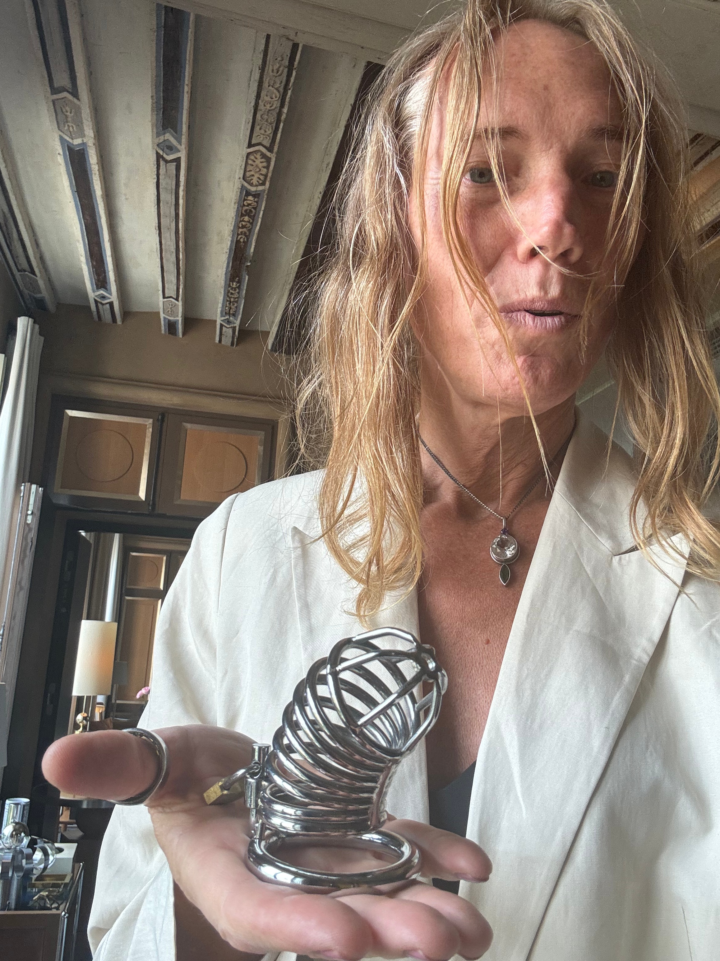 Silver chastity cage held in hand – symbol of Ritual Kink and devotion.